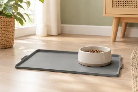 Tapis de gamelle gris en silicone avec bords relevés, posé sous un bol dans un intérieur lumineux.