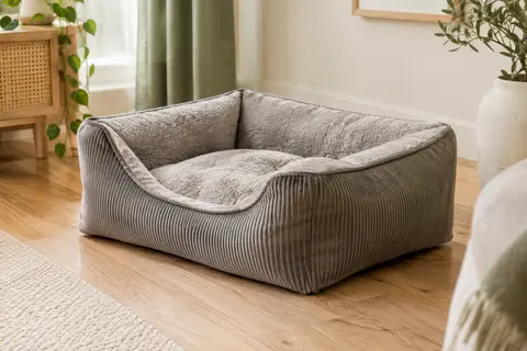 Panier rectangulaire gris chaud à trois rebords rembourrés, posé dans un intérieur lumineux aux tons naturels.